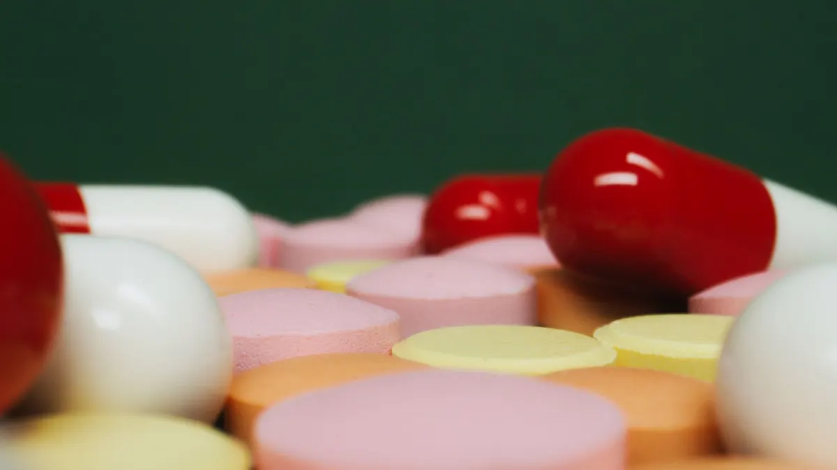 A close-up view of various colorful pills and tablets on a green background, focusing on medication variety.